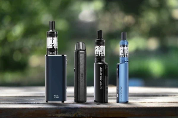 Quatre modèles de cigarettes électroniques de différents formats alignés sur une table