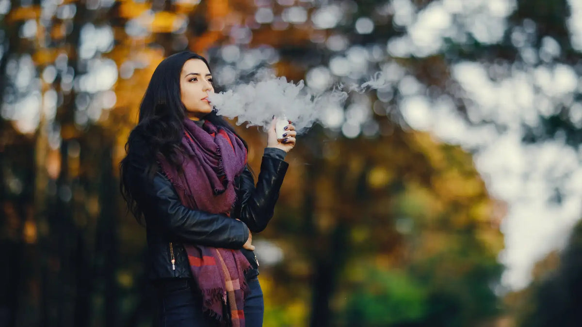 Vapoteuse produisant un nuage de vapeur dense en extérieur, décor automnal