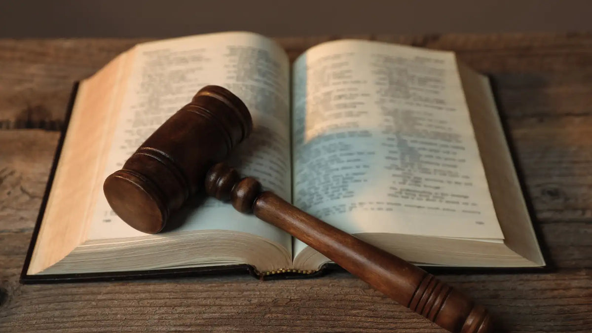 Marteau de juge et code posés sur une table, illustrant le cadre légal