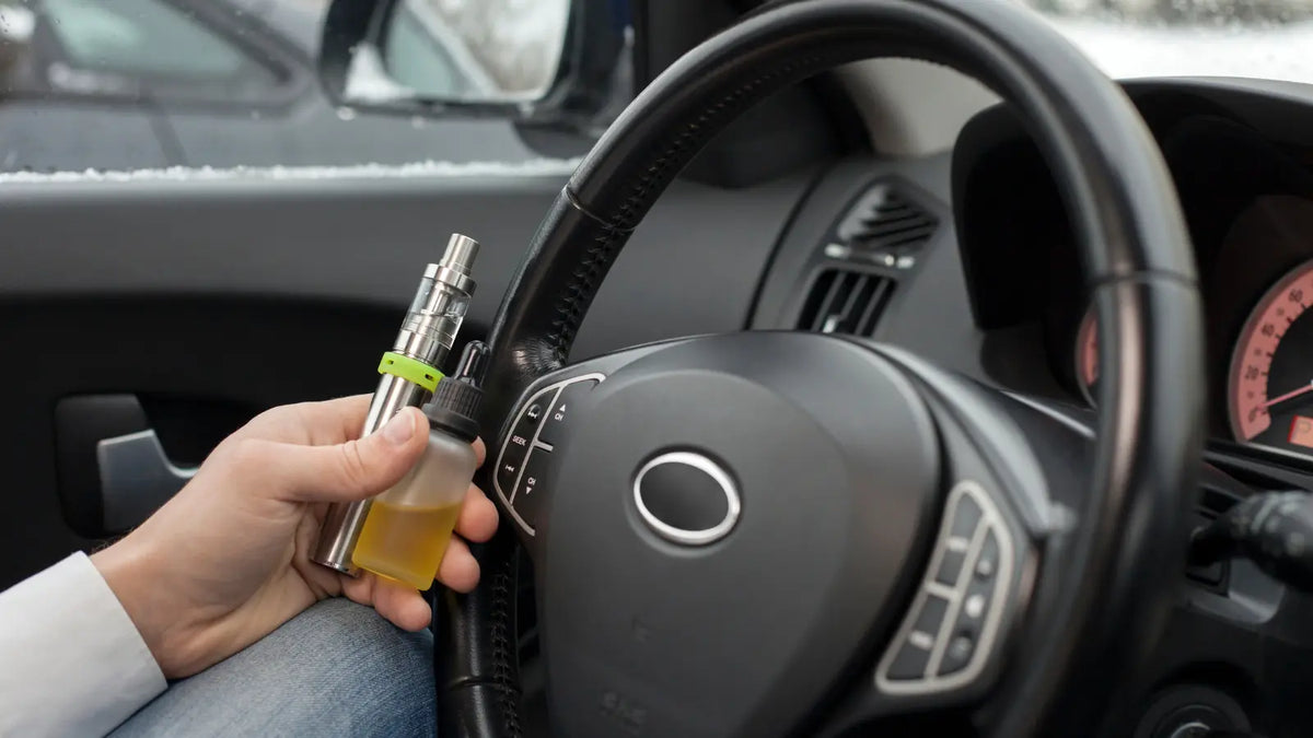 La main d'une personne tenant une cigarette électronique et un e-liquide en voiture